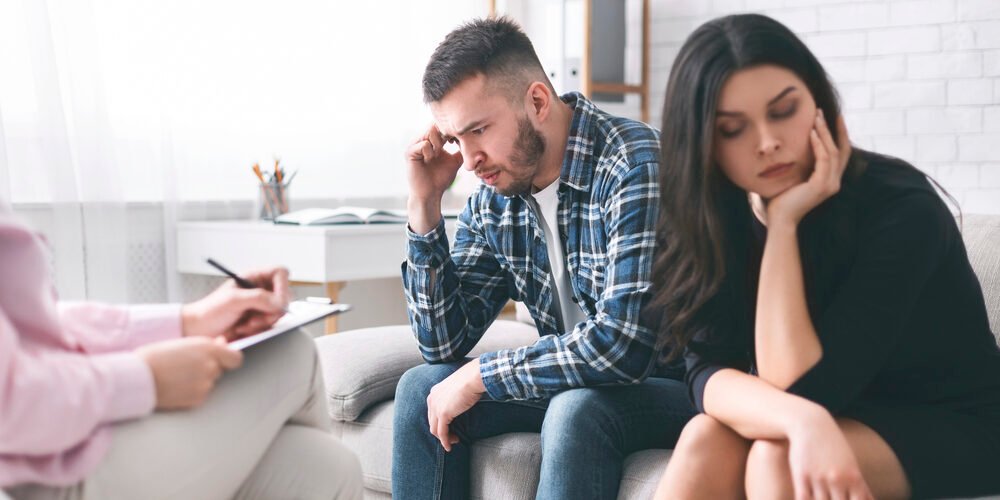 Stressed couple sitting separately at family counselor office
