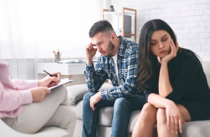 Stressed couple sitting separately at family counselor office