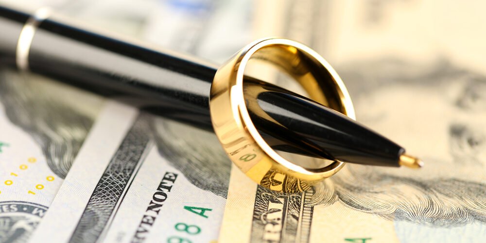 Wedding ring on pen, on banknotes background. Marriage of convenience