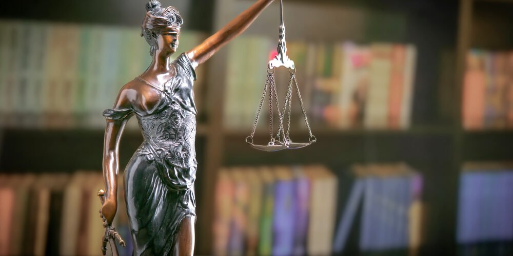 Goddess of justice statue in lawyer cabinet on bookshelf background