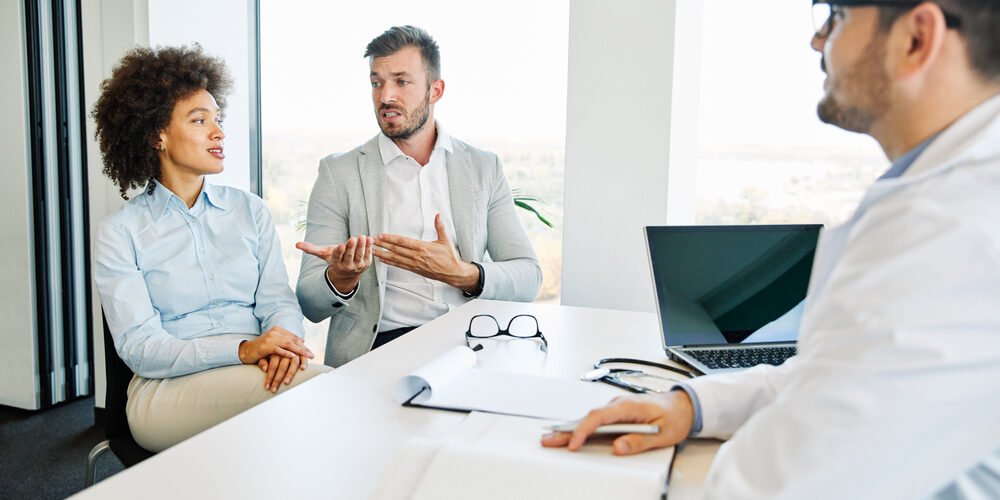Couple reviewing divorce paperwork with an attorney discussing health insurance coverage.