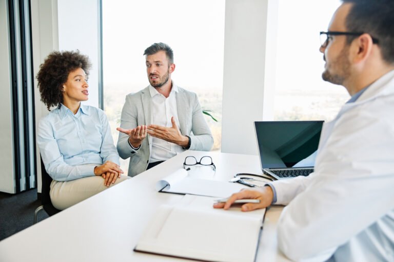 Couple reviewing divorce paperwork with an attorney discussing health insurance coverage. Couple reviewing divorce paperwork with an attorney discussing health insurance coverage.
