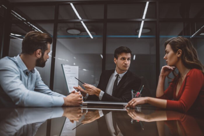 Lawyer pointing at a marital contract to spouses A mediator guiding a couple toward resolution during a New Jersey divorce mediation session.