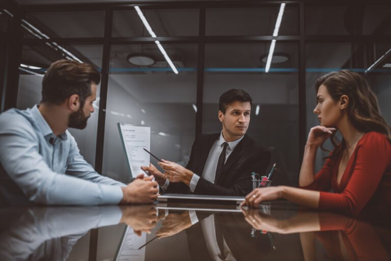 Lawyer pointing at a marital contract to spouses A mediator guiding a couple toward resolution during a New Jersey divorce mediation session.